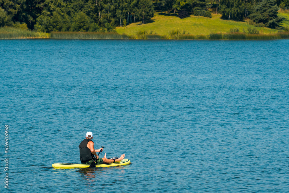 Side view foto of a man swimming and relaxing on the sup board