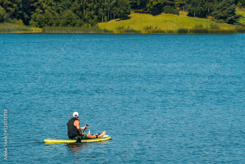 Side view foto of a man swimming and relaxing on the sup board