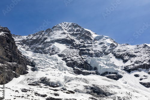 Side of the Jungfrau mountain in the Bernese Oberland in Switzerland. Large pieces of of glacial ice can be seen on the side of the mountain. 