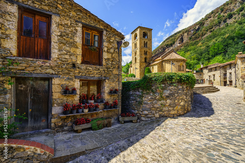 Fototapeta Naklejka Na Ścianę i Meble -  Picturesque alley with houses full of flowers and main square with Romanesque church in the mountain village of Beget, Catalonia.