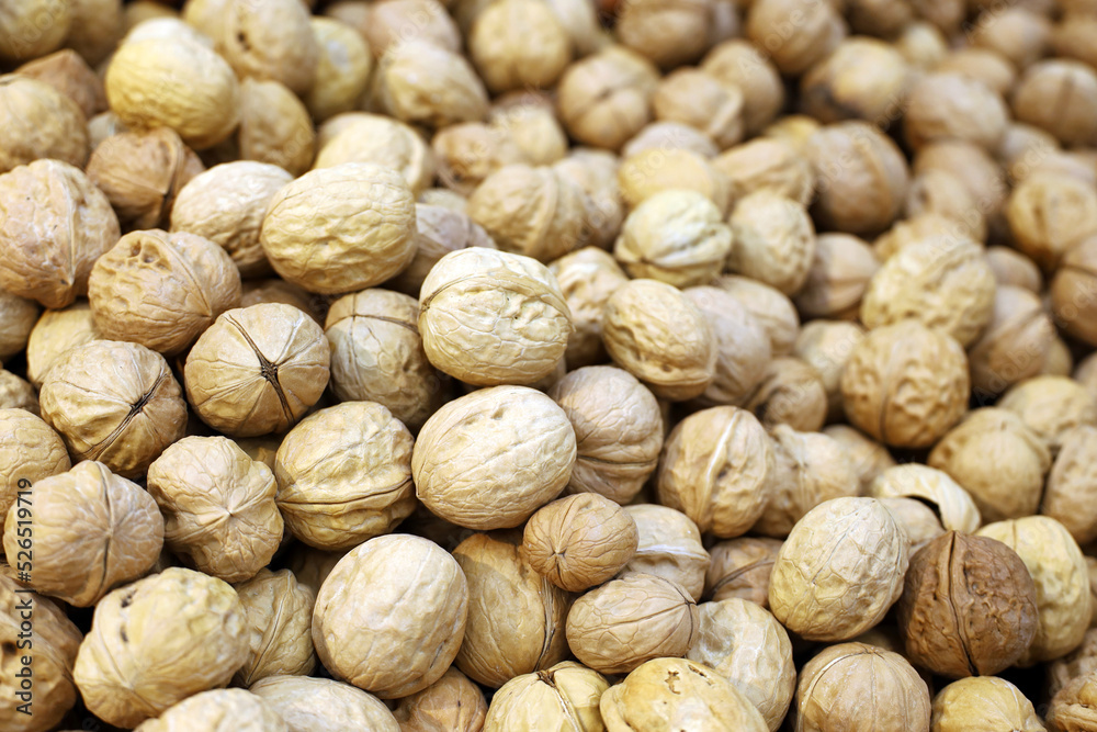 Walnuts heap for background. Dry nuts in shells on a market, protein food for brain health