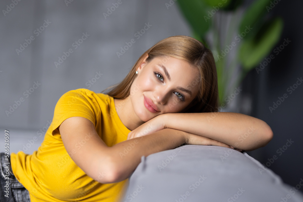 Fotografie Happy young woman lying on couch and relaxing at home