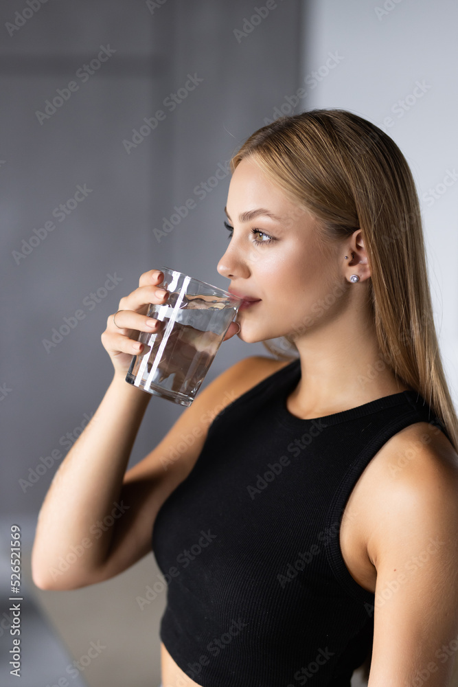 Young woman drinking water in the kitchen at home Young woman drinking water in the kitchen at home