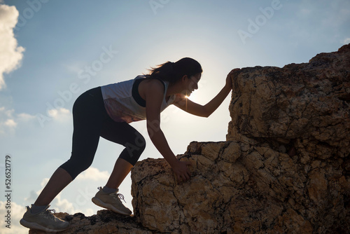 Silhouette athelete hiking woman climb to montain peak at sunset