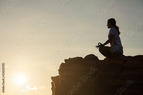 woman perform lotus yoga pose after climbing to top of mountain.