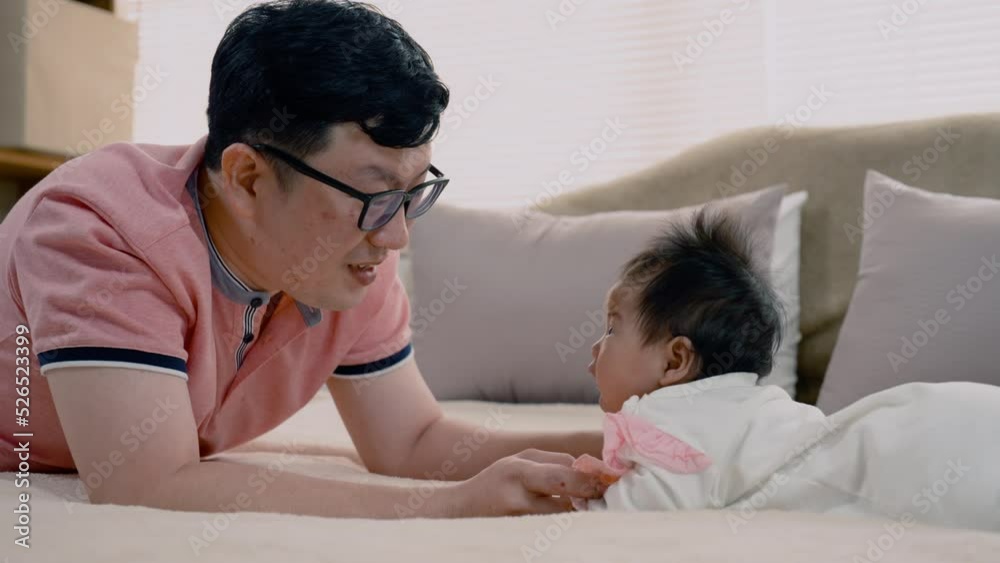 4K, Asian father, wearing a pink shirt, Father lies, and plays with his daughter, Cherishingly, a young girl lovingly looked at his father in disbelief, in a daze, with white pajamas. 4K, Asian father, wearing a pink shirt, Father lies, and plays with his daughter, Cherishingly, a young girl lovingly looked at his father in disbelief, in a daze, with white pajamas.