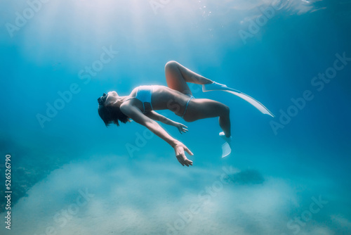 Free diver lady in bikini relax and glides with fins. Freediving and sunlight in transparent ocean