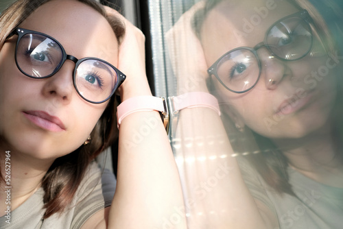 Portrait of young woman in glasses riding on train, looking at nature. Close up.