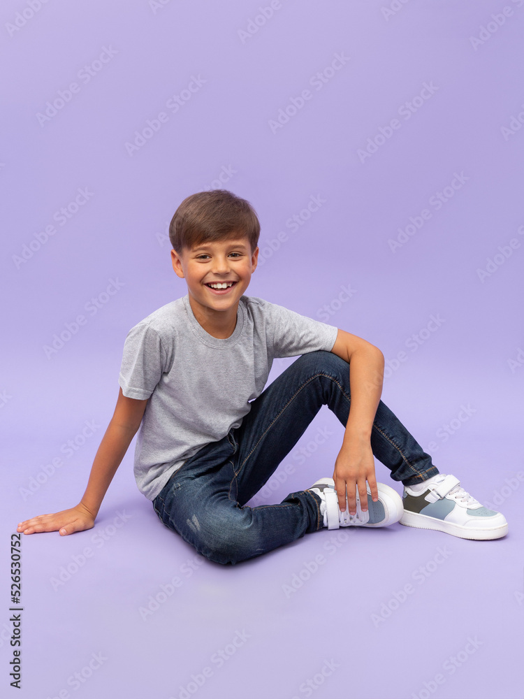 Portrait of young boy sitting isolated over a lilac background