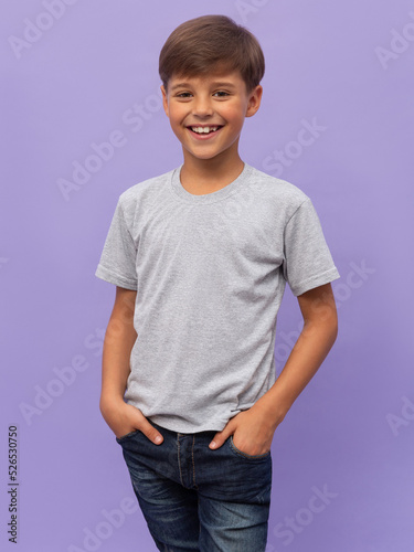 Obraz na płótnie Self assured child in casual clothes and socks holding hands in pockets and looking at camera against lilac background w salonie