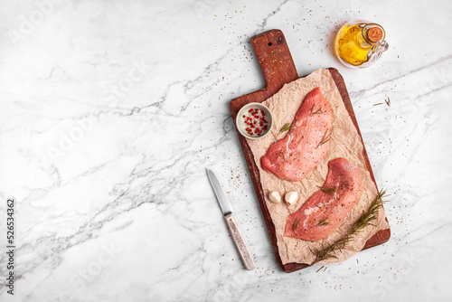 Two raw veal escalope on the old wooden cutting board, ready to cook, top view photo