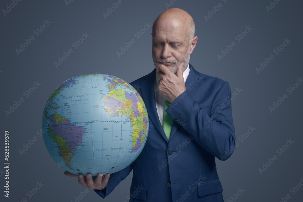 Business executive holding a globe and thinking Business executive holding a globe and thinking