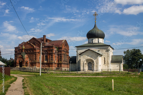 Yuryev-Polsky, Vladimir Region, Russia - August, 17, 2022: the white-stone St. George Church and the brick church of the Holy Trinity on a clear sunny summer day in the old town