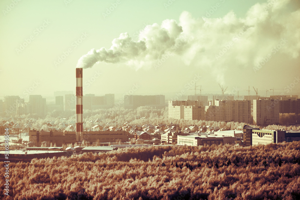 Factory chimney with smoke over winter city with houses in snow Factory chimney with smoke over winter city with houses in snow