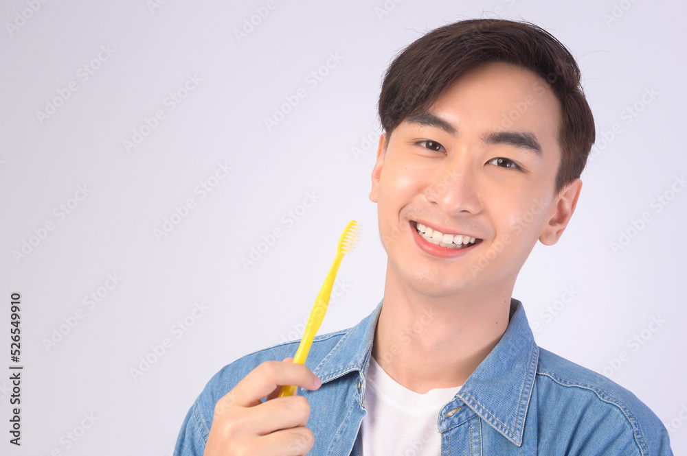 Young smiling man holding toothbrush over white background studio, dental healthcare and Orthodontic concept.. Young smiling man holding toothbrush over white background studio, dental healthcare and Orthodontic concept..