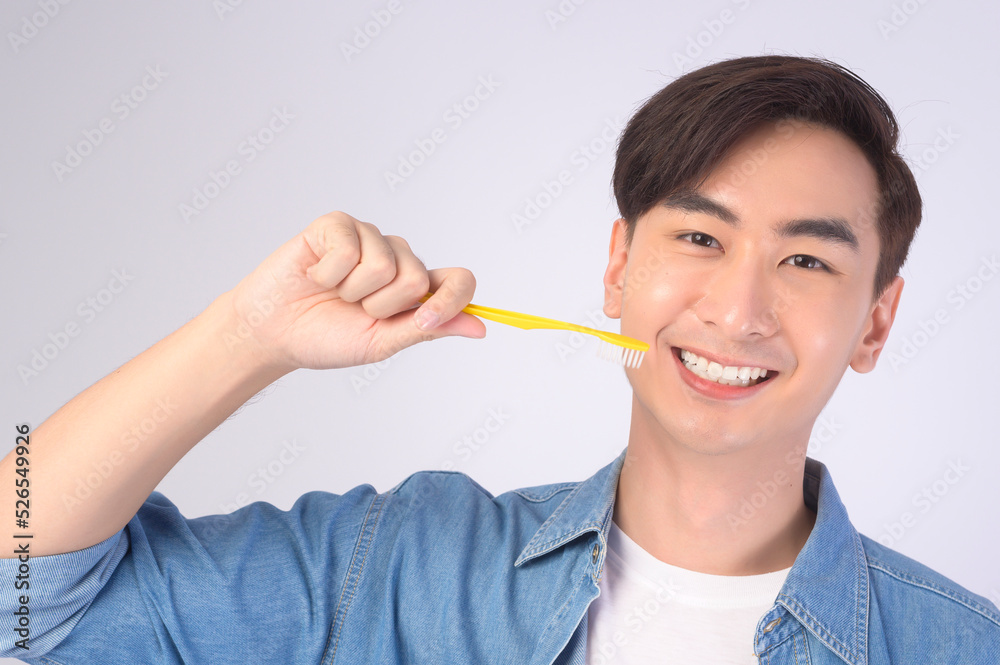 Young smiling man holding toothbrush over white background studio, dental healthcare and Orthodontic concept.. Young smiling man holding toothbrush over white background studio, dental healthcare and Orthodontic concept..