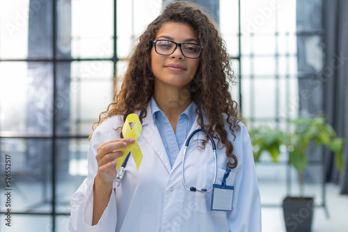 Doctor in a white uniform holds a yellow ribbon in her hand, symbol of the fight against the cat's tumor, problem of suicides and their prevention