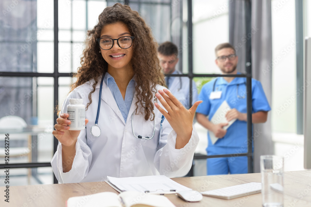 © ty - Pretty woman doctor therapist talking to web camera consulting virtual patient online by video conference call chat. Collegues are on the background.