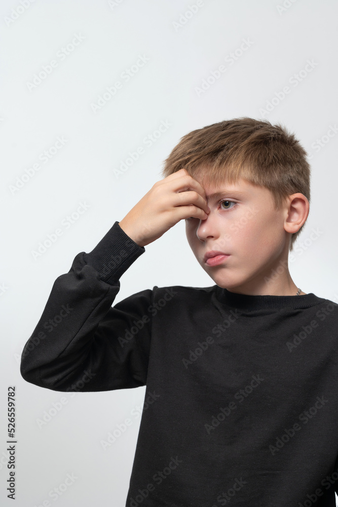 The child has a headache, the boy holds his hand on his forehead from a headache. The child has a headache, the boy holds his hand on his forehead from a headache.