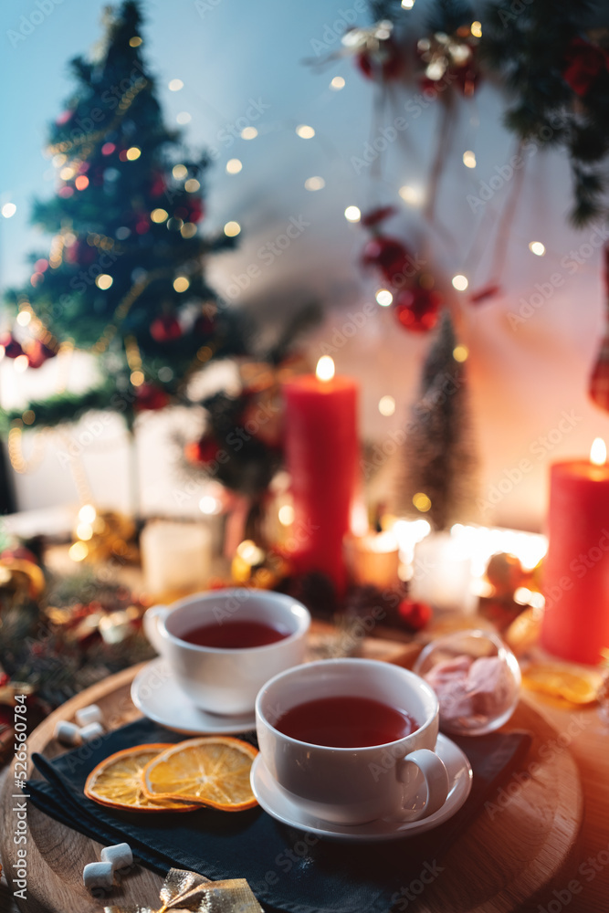 two cups of black or berry red hot english christmas tea with decor and candle