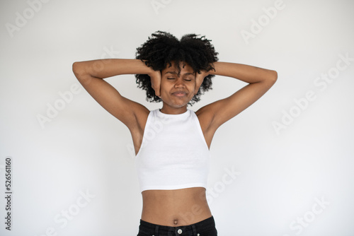 Portrait of carefree African American woman with hands at head. Young girl wearing white crop top and jeans standing against white background. Happiness concept © KAMPUS