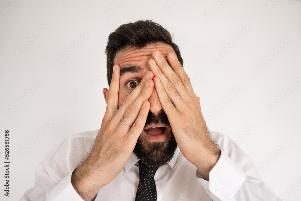 Portrait of scared bearded man. Male in shirt covering face with surprise. Portrait, emotion concept Portrait of scared bearded man. Male in shirt covering face with surprise. Portrait, emotion concept