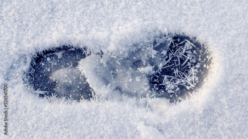 A human footprint in the snow and large snowflakes