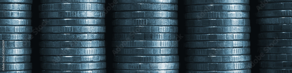 Obraz premium Stack of coins close-up. Coin texture. Blue tinted business banner made of many coin edge. Economy finance and bank header. Abstract money wall. Tax, credit and currency change. Macro