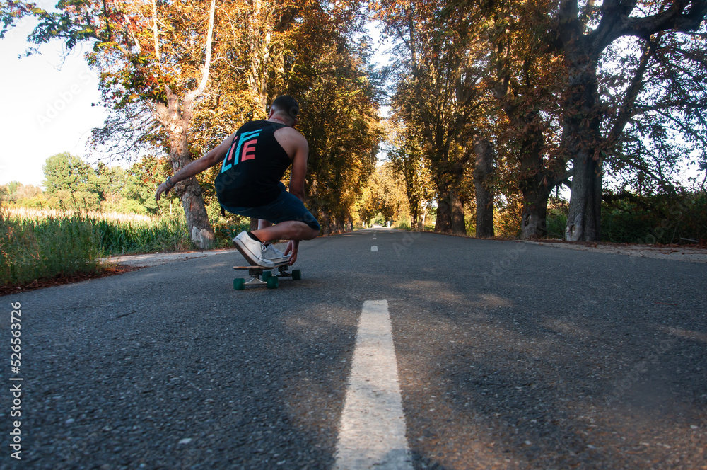 Obraz premium man on surfskate, surfing the highway, in a small town , nature