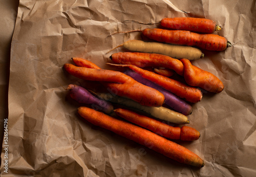 Lots of organic colorful carrots in a pile on craft paper. Organic ugly vegetables. Top view with copy space