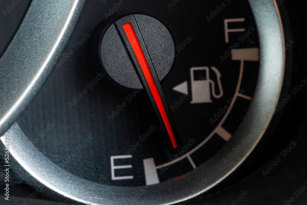 Naklejka premium Low fuel gauge on car dashboard, close-up.