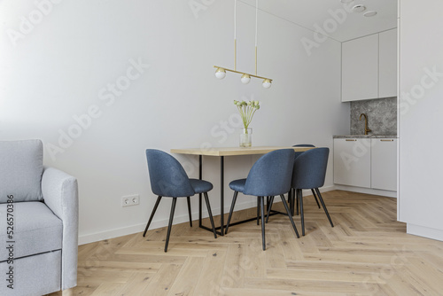 Modern minimalist kitchen and dining room interior design  with wooden furniture, oak floor. blue chairs.  Aesthetic simple interior design concept.