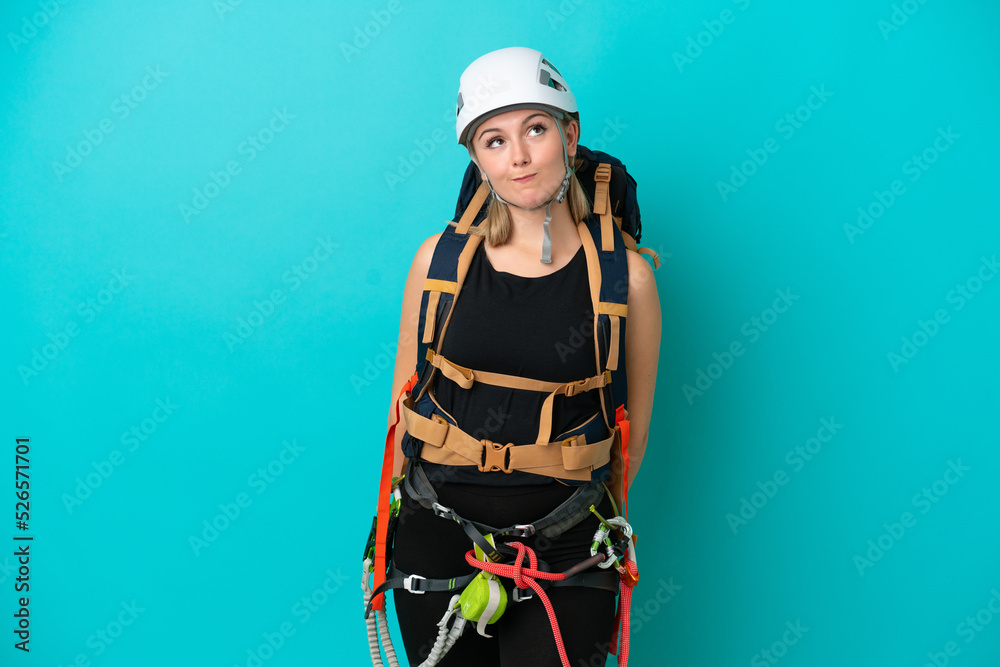 Young caucasian rock climber woman isolated on blue background and looking up