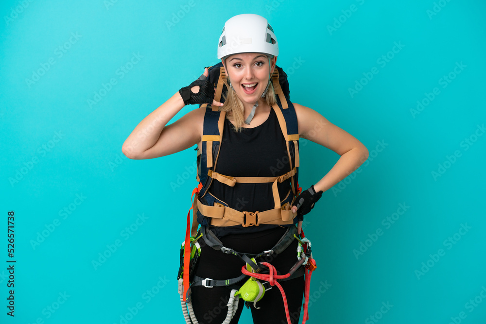Young caucasian rock climber woman isolated on blue background making phone gesture. Call me back sign Young caucasian rock climber woman isolated on blue background making phone gesture. Call me back sign