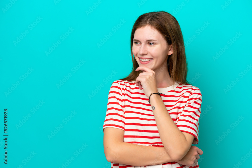 Young English woman isolated on blue background looking to the side and smiling