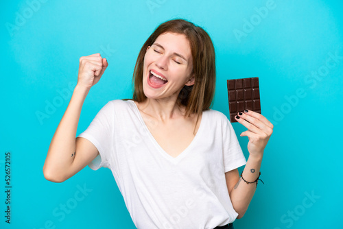 Young English woman with chocolat isolated on blue background celebrating a victory