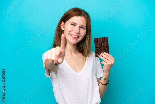Young English woman with chocolat isolated on blue background showing and lifting a finger