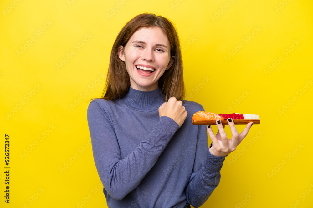 Young English woman holding sashimi isolated on yellow background celebrating a victory Young English woman holding sashimi isolated on yellow background celebrating a victory