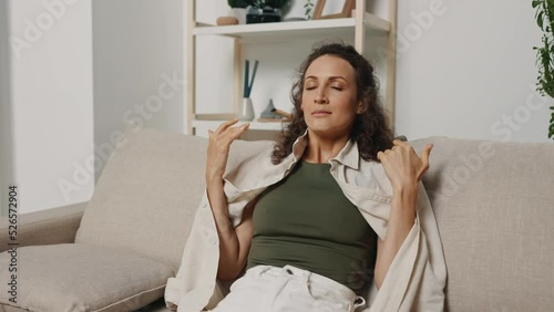 A woman tries to calm her nerves and her mental health by breathing practices on the couch at home