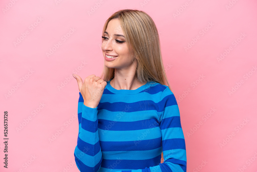 Pretty blonde woman isolated on pink background pointing to the side to present a product Pretty blonde woman isolated on pink background pointing to the side to present a product