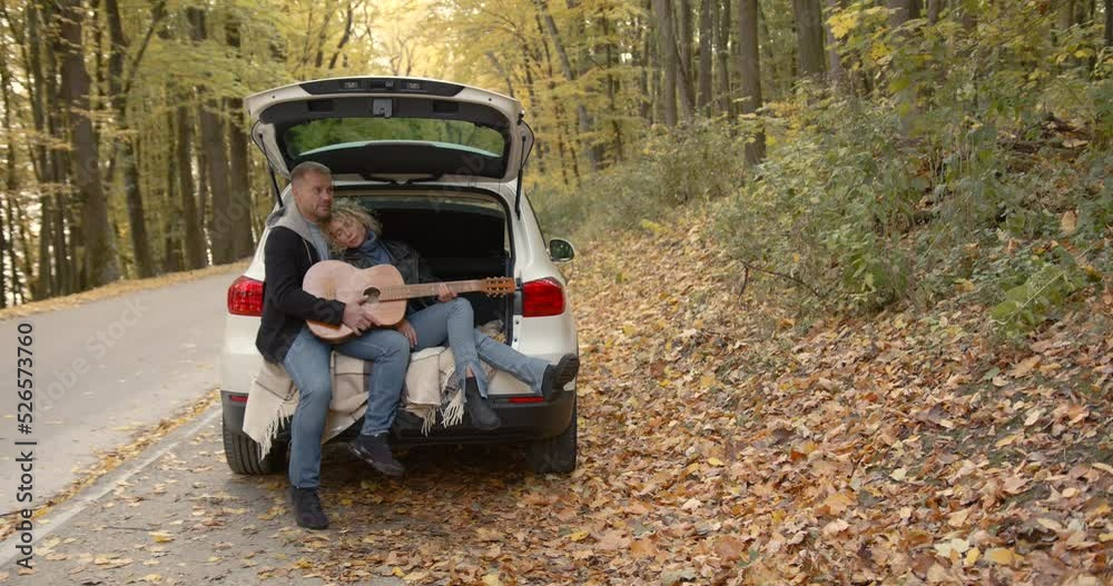 Happy couple sitting in a car in the autumn park Happy couple sitting in a car in the autumn park