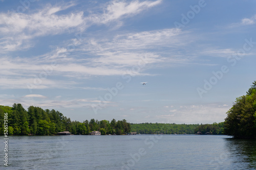 Sea plane landing on on tranquil Lake Joseph, Muskoka, Ontario Canada. Cottages are visible along the lake. © AC Photography