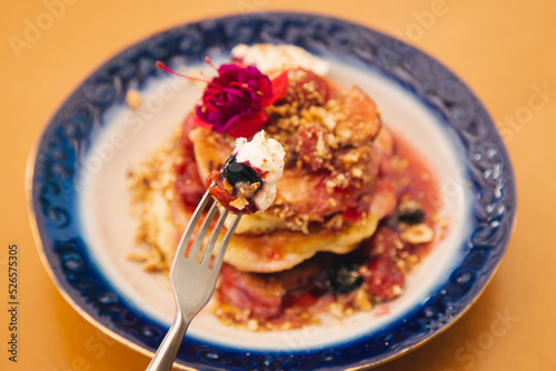 Appetizing pancakes decorated with berries and flowers.
