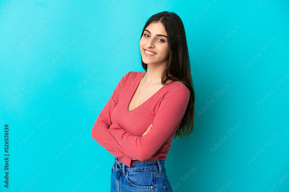 Young caucasian woman isolated on blue background with arms crossed and looking forward Young caucasian woman isolated on blue background with arms crossed and looking forward