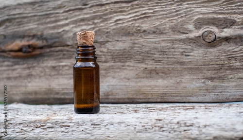Small brown glass medicine bottle on aged wood background. Essential oil. 