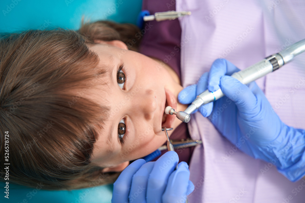 Pedodontist is performing teeth-polishing procedure on child