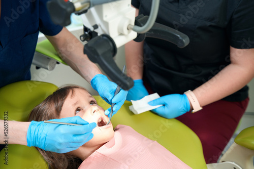 Pediatric dentist examining patient oral cavity with modern diagnostic equipment