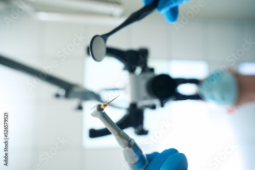 Professional endodontist performing tooth nerve removal under microscope photo