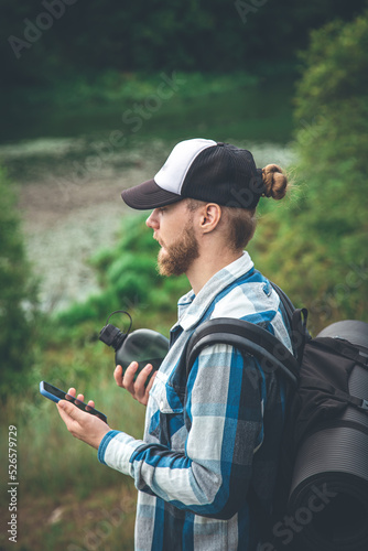 A male traveler with a backpack looks into a smartphone.