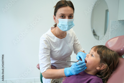 Pediatric dentist posing for camera during patient oral cavity examination